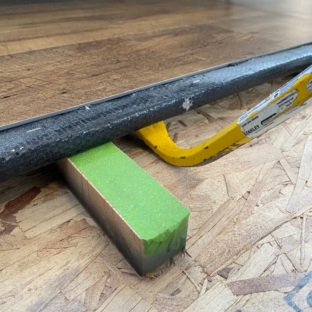 Close up view of a crowbar lifting an RV slide-out to install new RV flooring