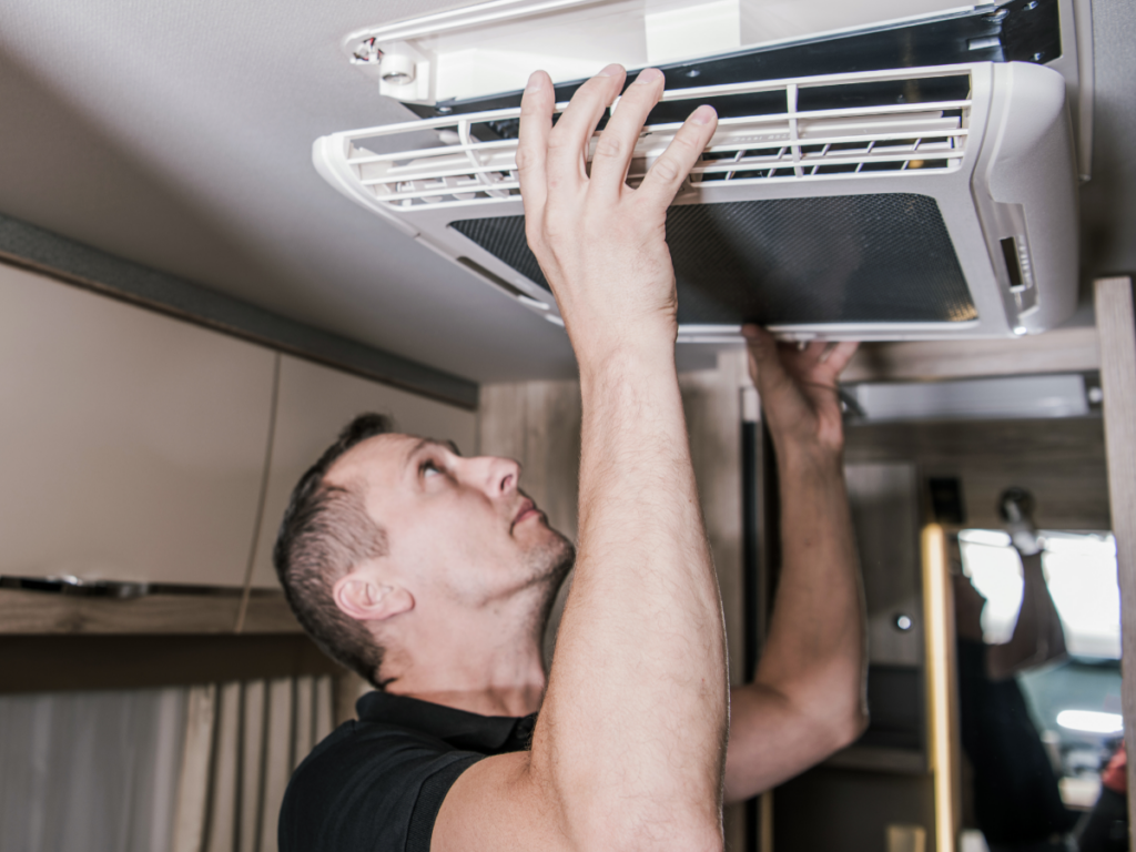 A man inspects the air conditioning in an RV