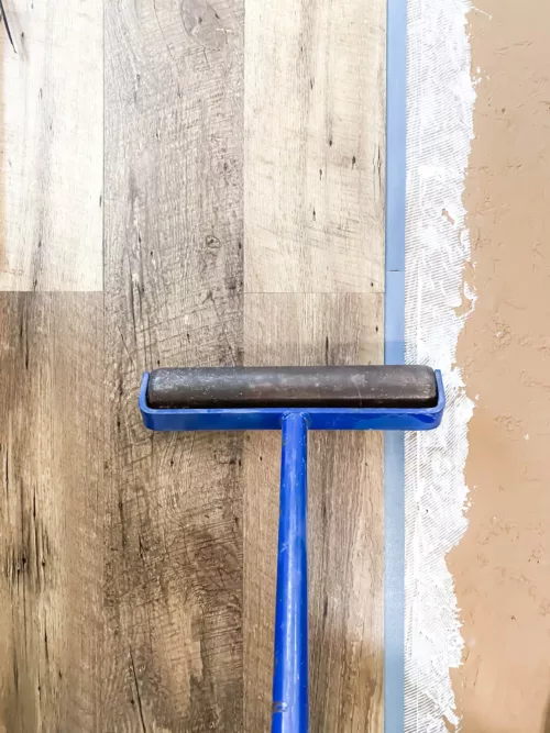 Rolling the vinyl flooring with a flooring roller