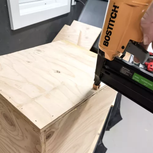 Hand using a Brad Nailer to nail plywood together