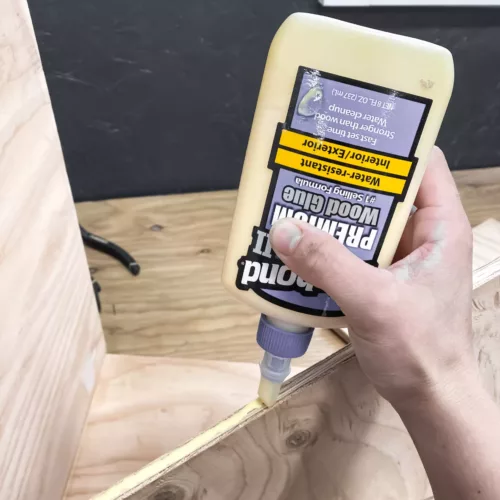 Hand applying wood glue to plywood