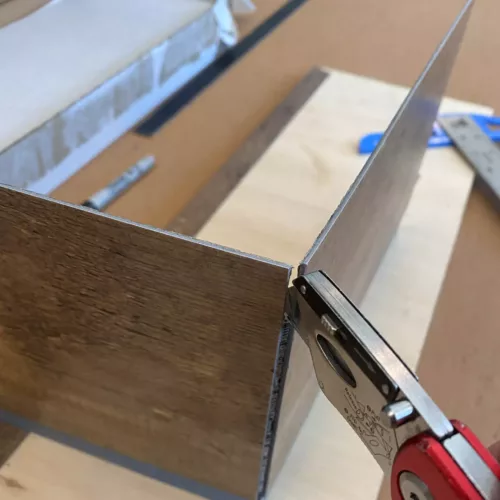 Cutting a vinyl flooring plank with a razor